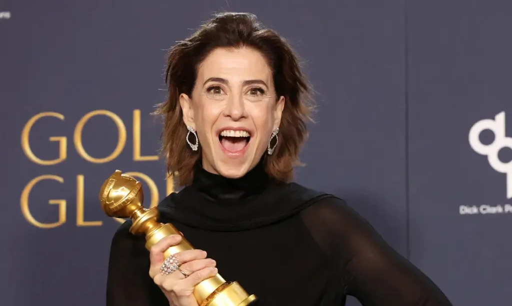 Atriz sorridente segurando troféu em premiação