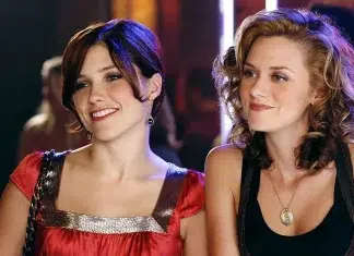 Duas mulheres sorrindo em evento social noturno.