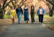 Mulheres estilosas caminhando em parque florido.