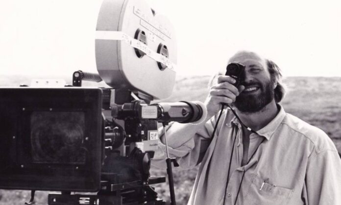 Cineasta sorrindo operando câmera de filme ao ar livre