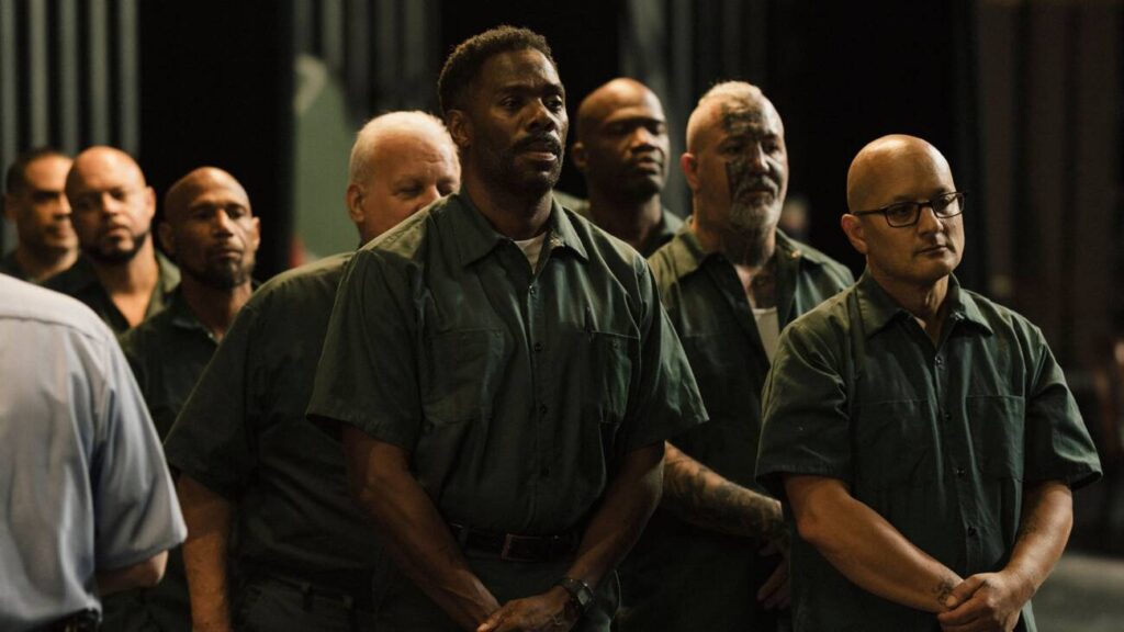 Grupo de homens de uniforme em fila, olhando sérios.