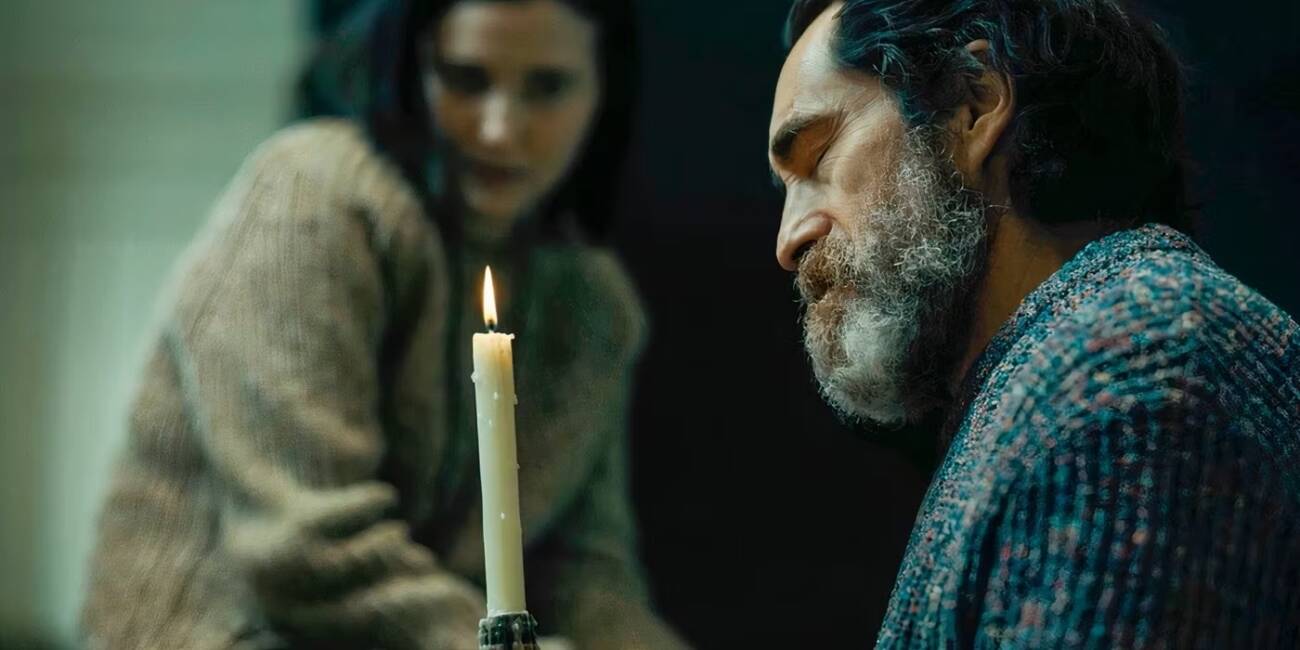 demian bichir stares at a candle while julia goldani telles stares in the background in beacon