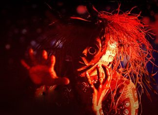 A Fúria A masked, horror-style figure with straw-like hair reaching toward the camera in red lighting.