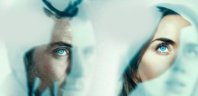 Two people gaze through a frosted, bluish glass, their blue eyes visible.