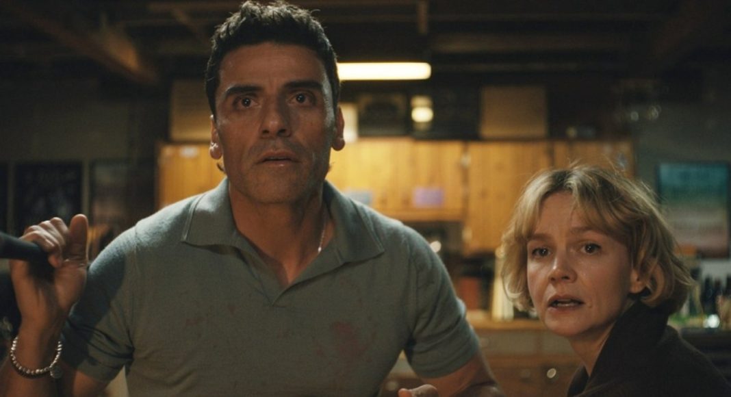 Two adults in a dimly lit kitchen/basement look terrified and alert, as if facing danger together.