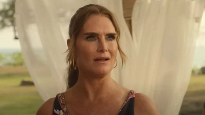 Concerned woman with hoop earrings in a floral dress outdoors, framed by sheer white curtains behind her.