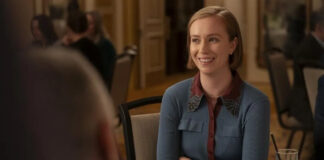 Smiling woman in a blue cardigan sits at a dining table during a social event.