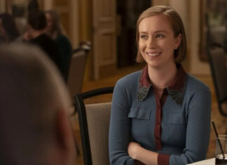 Smiling woman in a blue cardigan sits at a dining table during a social event.