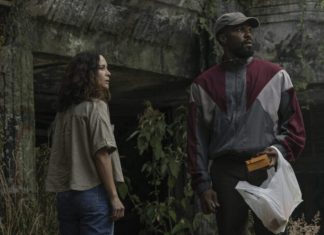 ‘Homem em Chamas’: Série da Netflix estrelada por Yahya Abdul-Mateen II e Alice Braga conquista 57% de aprovação no Rotten Tomatoes; Confira as avaliações! Two adults stand outside by a mossy concrete wall; the man in a color-block windbreaker holds a yellow envelope and a plastic bag while the woman watches nearby.
