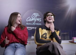 Two friends sit and laugh on a set, with an 'Off Campus' logo in the background; woman in red shirt, man in a yellow-and-black sweater sits to her right, wearing sunglasses.