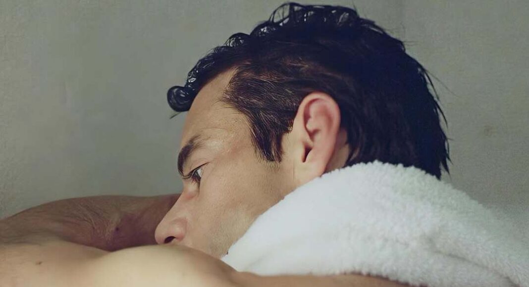The Man I Love 03 (2) Close-up side profile of a man resting his head on a white towel over his shoulder.