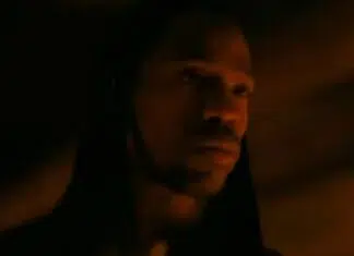 ‘A Odisseia’: Christopher Nolan DEFENDE escalação de Travis Scott para o épico Hooded man in low, orange light with a contemplative expression (close-up)