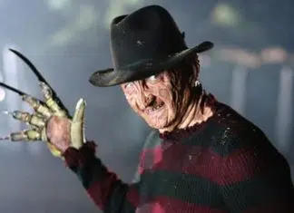 Freddy Krueger wearing a fedora and striped sweater, glove with blades raised toward the camera.