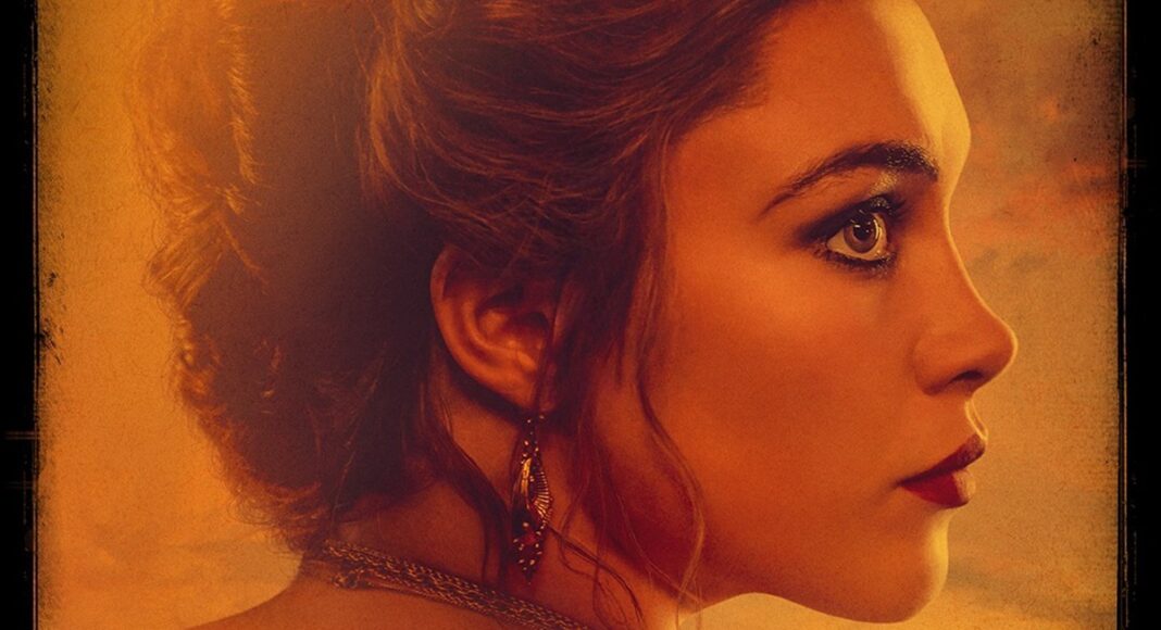Close-up profile of a woman with an elegant updo, wearing a necklace and dangling earring, bathed in warm amber light.