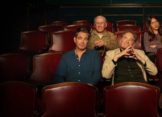 Liga a TV e aproveita: Essas 10 Dicas de Séries que vão te SURPREENDER! Six people sit in a theater row of red seats, smiling at the camera.