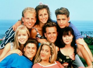 Fenômeno nos anos 90, ‘Barrados no Baile’ estreia fazendo sucesso na Netflix e mostra a elite de Beverly Hills Group of eight young friends posing closely for a photo outdoors by the coast, all smiling under a bright blue sky.
