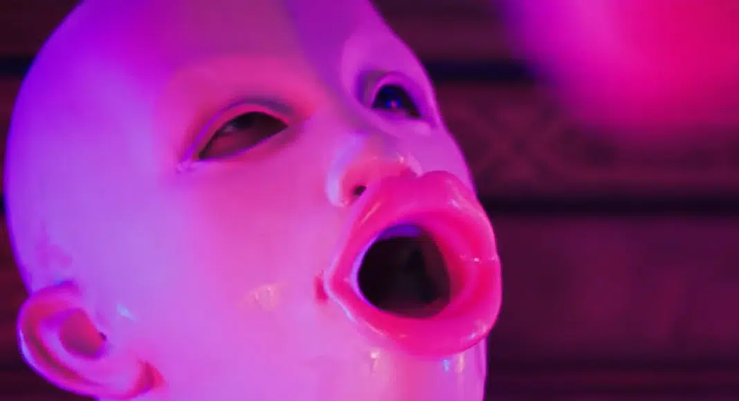 blowie Close-up of a person wearing a glossy pink pig-nose mask, mouth open, under magenta stage lighting.
