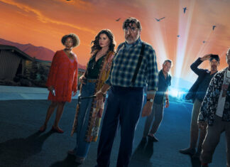 Confira o ARREPIANTE trailer inédito de ‘The Boroughs’, nova série sobrenatural dos criadores de ‘Stranger Things’ Six adults stand together on a suburban street at sunset, a bright beam of light behind them suggesting a sci‑fi poster vibe.