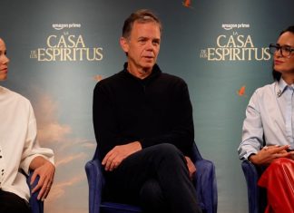 Three panelists seated on stage during a discussion at a La Casa de los Espíritus event. backdrop shows the show's title.