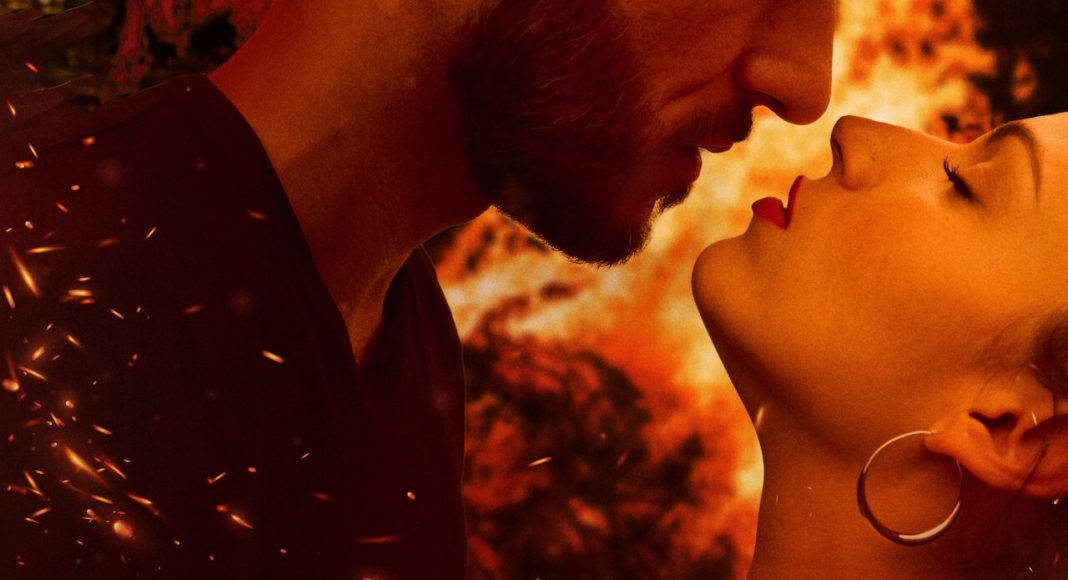 Close-up of a couple about to kiss, warm orange light and embers floating around.
