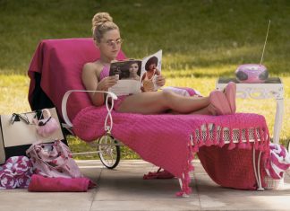 Woman sunbathing on a pink chaise lounge outdoors, reading a magazine with a pink throw, surrounded by pink accessories and a pink mini radio.