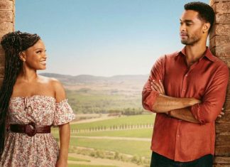 Crítica | Eu & Você na Toscana – Romance com Astros de ‘A Pequena Sereia’ e ‘Os Bridgertons’ Não Harmoniza no Sabor Woman in a floral off-shoulder dress with a belt smiles at a man in a red shirt as they stand between stone pillars with a rural landscape behind them.