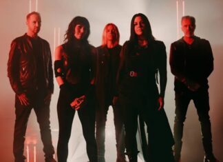 A five-member rock band posing in a dimly lit studio with red lighting and edgy outfits, facing the camera confidently.