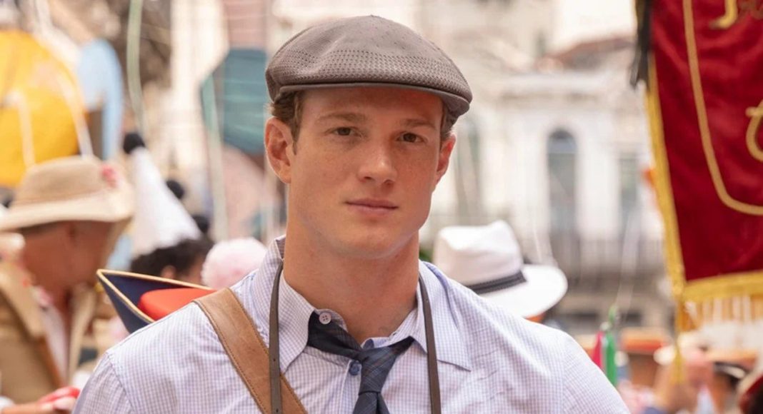 Young man in a gray flat cap, checkered shirt, and tie at a crowded street festival