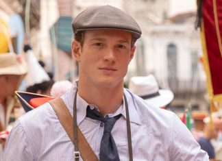Young man in a gray flat cap, checkered shirt, and tie at a crowded street festival