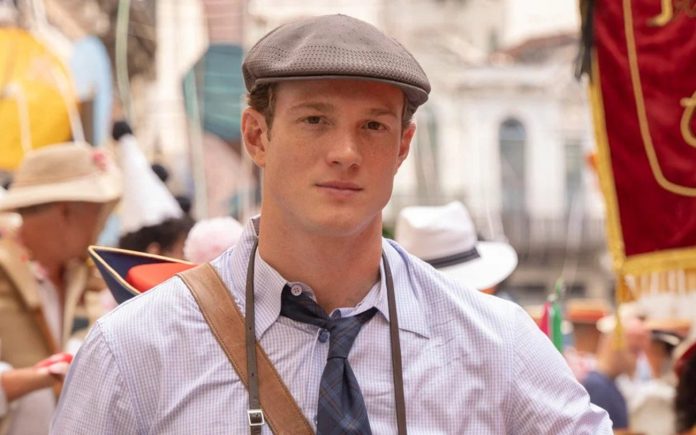Young man in a gray flat cap, checkered shirt, and tie at a crowded street festival
