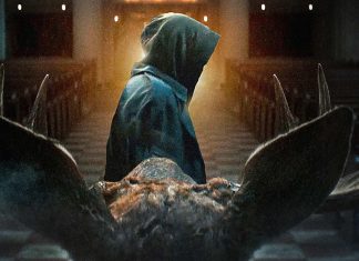 Hooded figure in a cloak stands at the end of a church aisle, viewed from behind, with a large animal skull in the foreground.