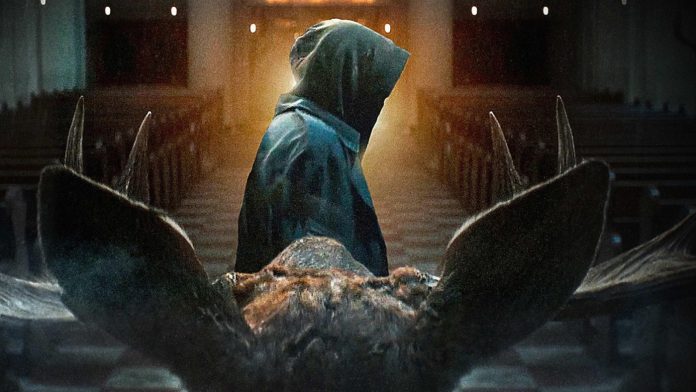 Hooded figure in a cloak stands at the end of a church aisle, viewed from behind, with a large animal skull in the foreground.