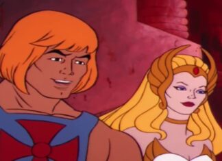 He-Man with orange hair and blue armor stands beside She-Ra in a pink, cavern-like setting, smiling.