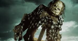 Zombie scarecrow in torn plaid shirt, standing in a dark, stormy sky overcast with greenish light.