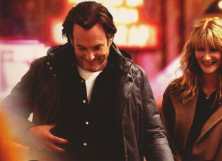 Man and woman smiling while walking together at night in a warmly lit street]