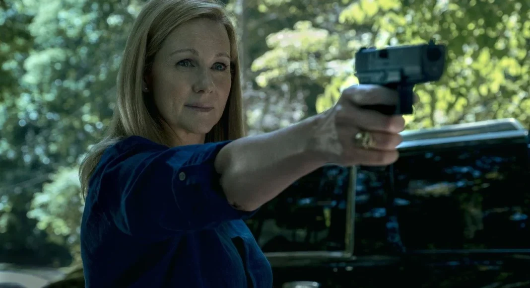 launa linney Woman in a blue shirt is pointing a handgun outward, outdoors with a dark SUV visible behind her.