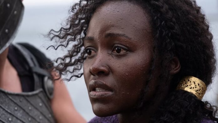Close-up of a dark-skinned woman with wet skin and curly hair, looking distressed at a figure in armor to her left, wearing a gold hair cuff.