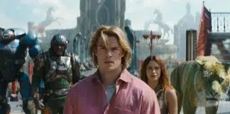 Film still: a man in a pink shirt leads a diverse group through a bustling fantasy city with a tiger nearby. (Note: concise summary focusing on the scene and characters.)