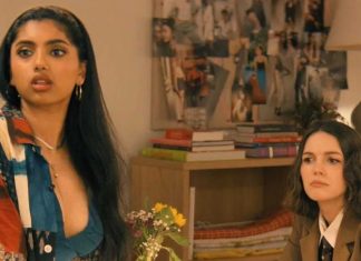 Two women in a living room: one with long dark hair in a colorful patchwork shirt speaks, the other in a brown blazer listens nearby.
