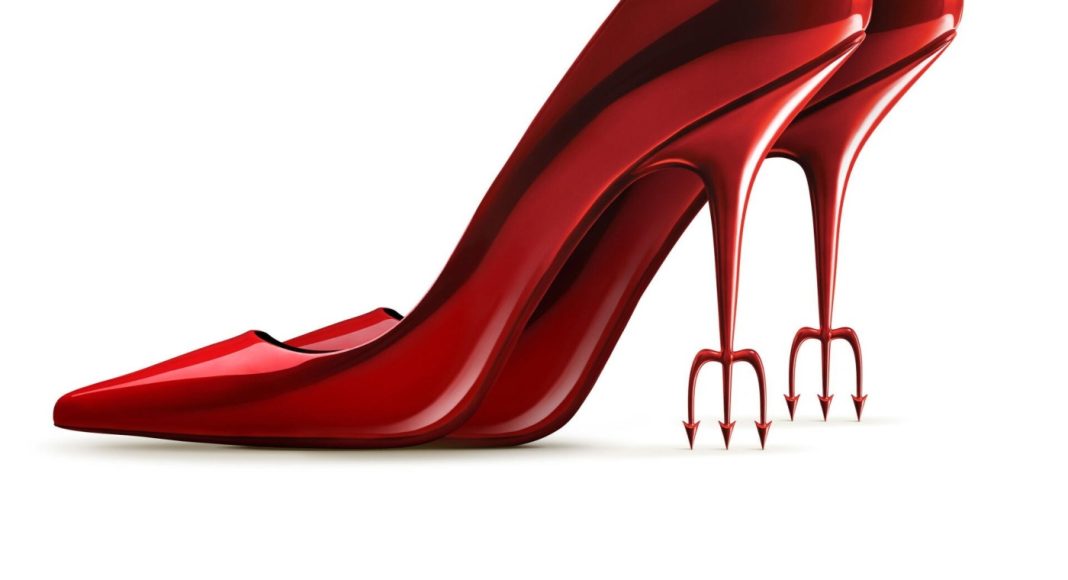 Red patent leather high-heeled shoe with forked, trident-like heels.