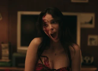 Woman with blood on her face screaming in a dimly lit room.