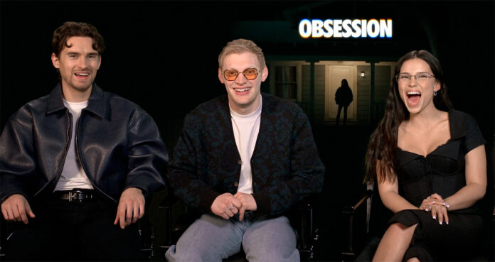 Three people sit and smile on a talk-show set; a glowing OBSESSION sign is behind them.