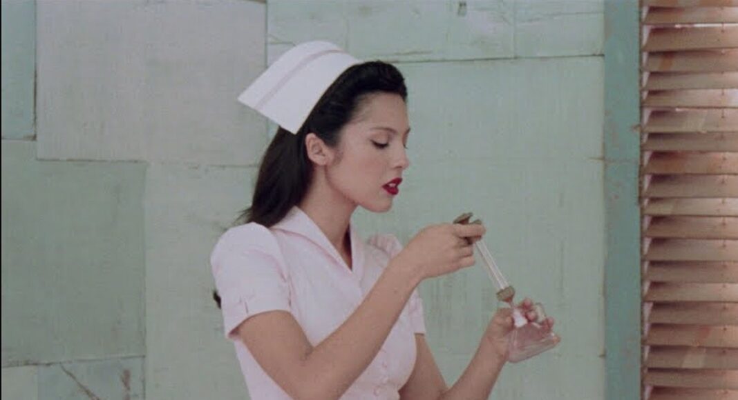 Young woman in a white nurse uniform and hat uses a dropper to transfer liquid into a small glass on a tray.