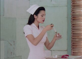 Young woman in a white nurse uniform and hat uses a dropper to transfer liquid into a small glass on a tray.