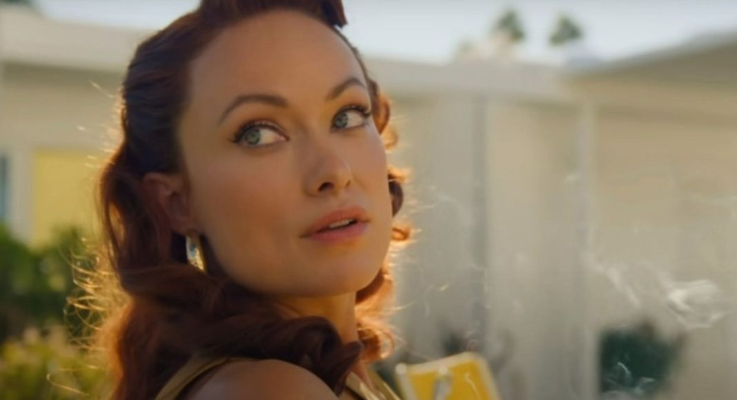 olivia wilde 3 Close-up of a woman with wavy red hair looking over her shoulder in warm sunlight outdoors, wearing earrings.