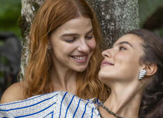 ‘Três Graças’: Após fenômeno nas redes, Alanis Guillen e Gabriela Medvedovsky NÃO renovam com a Globo Two women lean on a tree, smiling lovingly at each other outdoors.