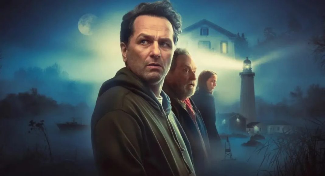 widow's bay 2 Four adults stand in a misty coastal town at night, with a lighthouse and moonlit sky in the background, suggesting a movie poster.