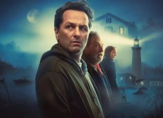 Four adults stand in a misty coastal town at night, with a lighthouse and moonlit sky in the background, suggesting a movie poster.