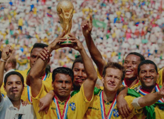 "A player on Brazil's 1994 World Cup team holding up the World Cup Trophy with his teammates standing next to him."