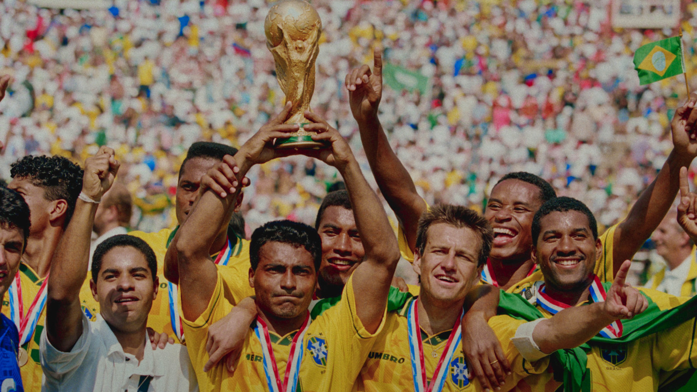 "A player on Brazil's 1994 World Cup team holding up the World Cup Trophy with his teammates standing next to him."